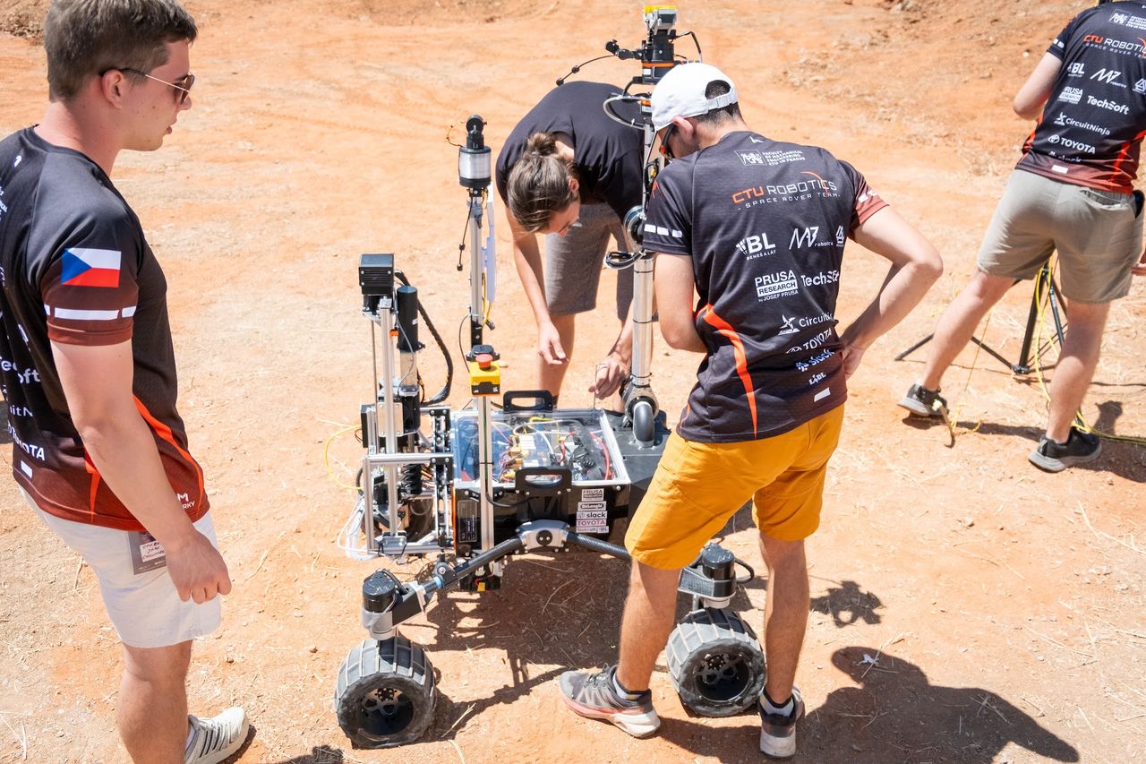 Team members working on Perun Gen 3 on red terrain during the science mission