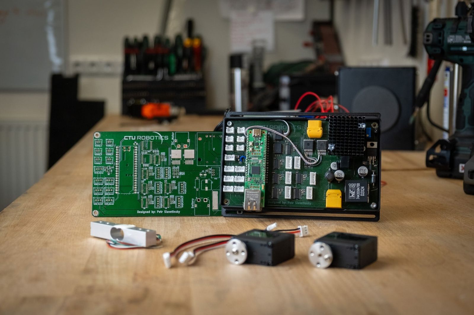 Two CTU Robotics control boards on a workbench, with a load cell and two servos