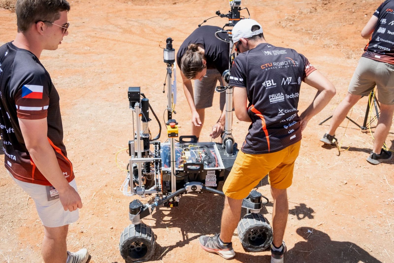 CTU Robotics team members working on the rover's electronics on red terrain